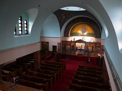 The nave at Archangels seen from the balcony, with a red carpet leading toward the altar.